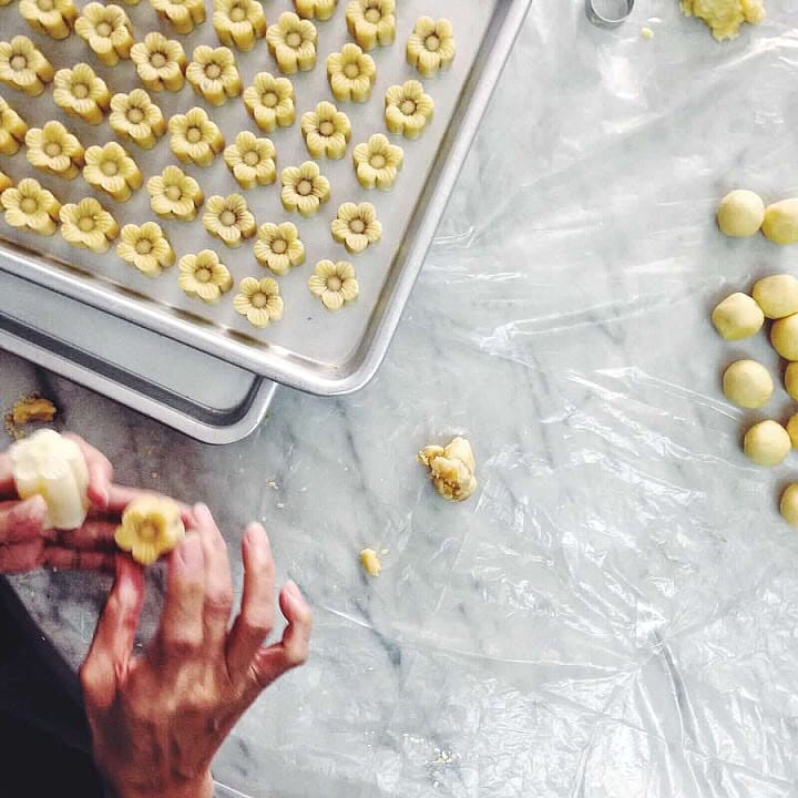 Hands shaping tarts on a tray